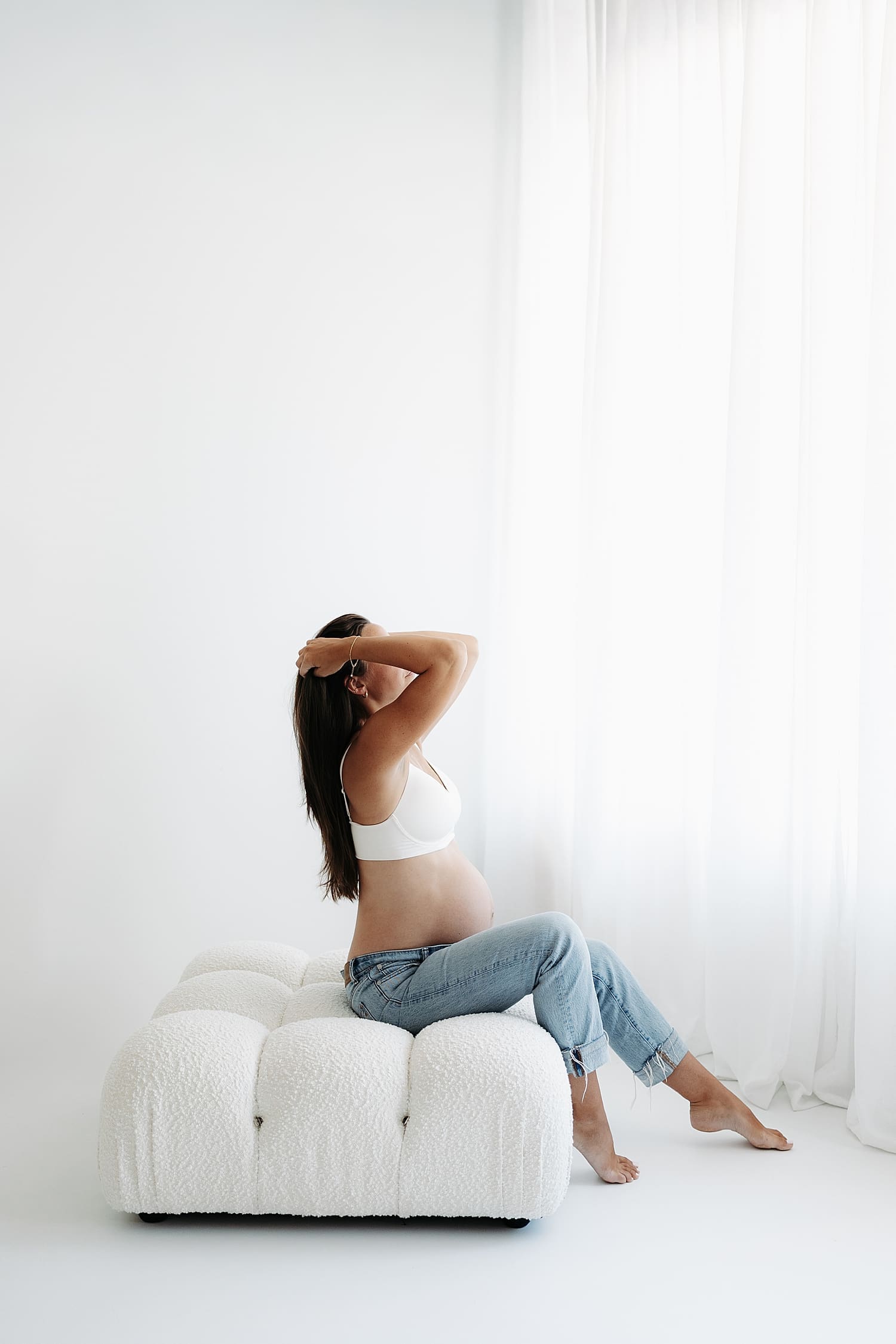 brunette runs her fingers through her hair on ottomon by Rose and Oak Photography 
