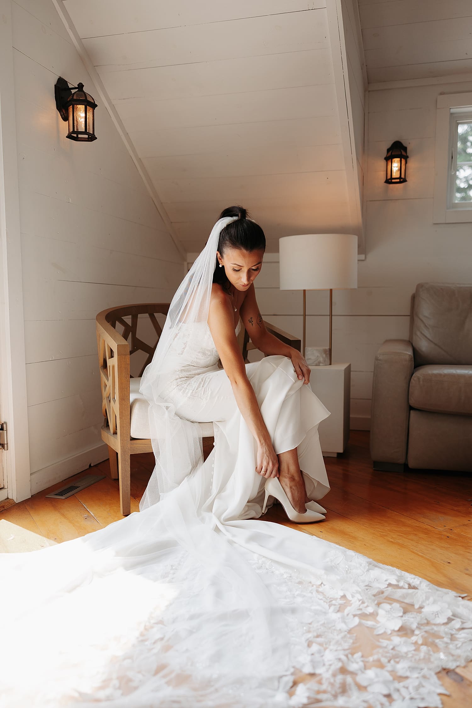 woman kneels down to adjust her white heel in getting ready room by Wisconsin wedding photographer