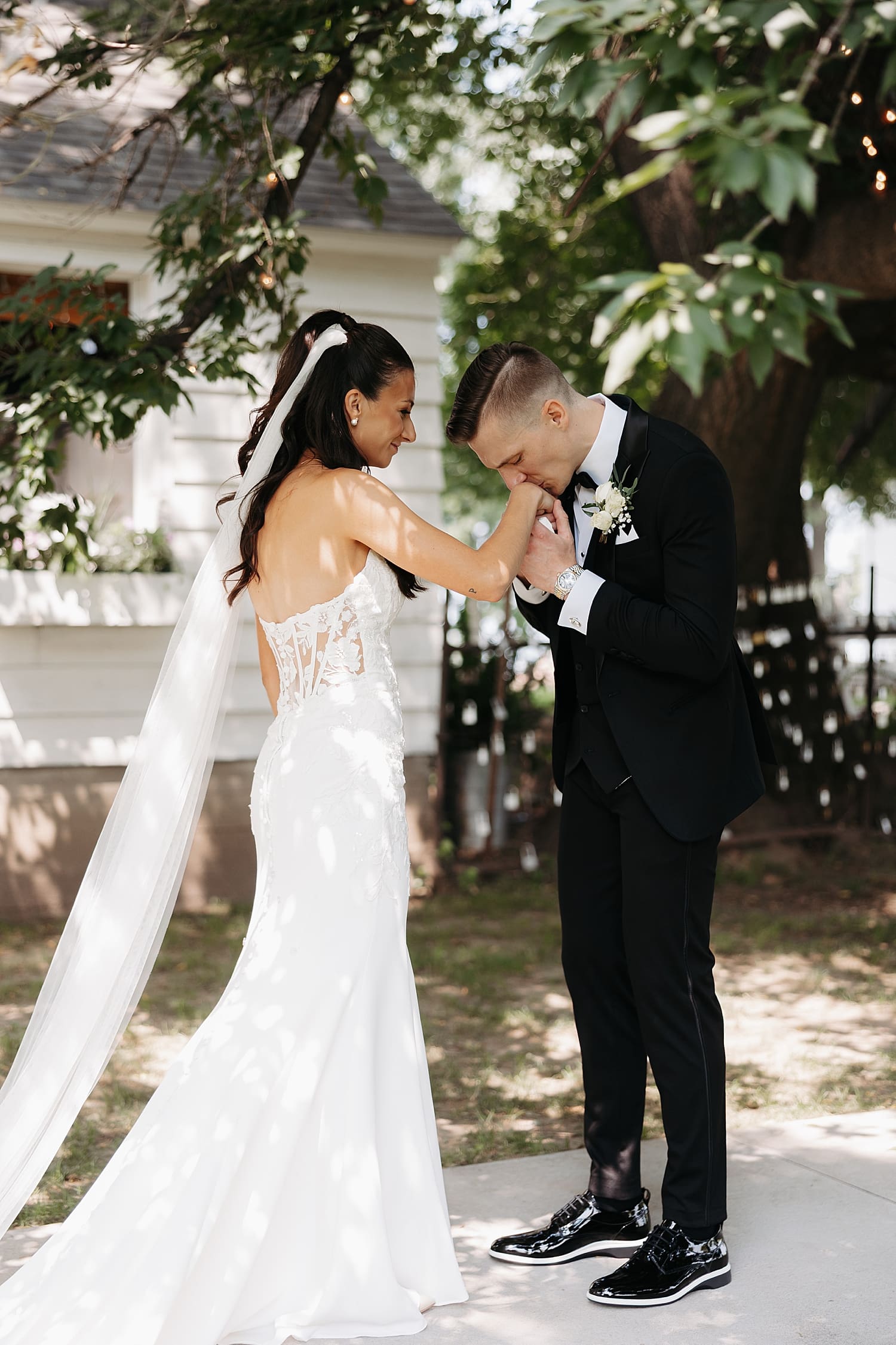 man kisses his fiance's hand during first look outside by Wisconsin wedding photographer