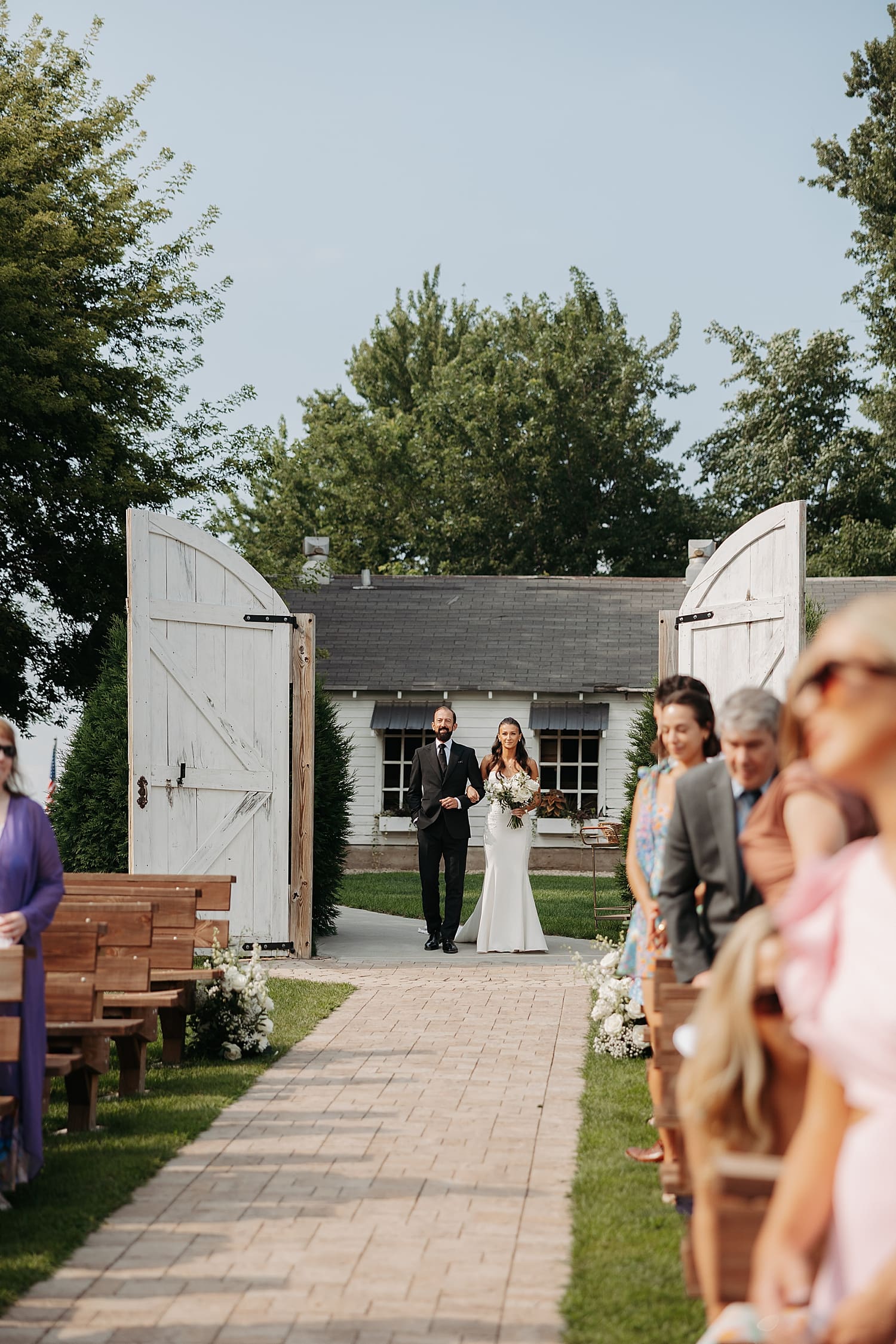 woman walks down outdoor aisle at Minnesota venue by Rose and Oak Photography