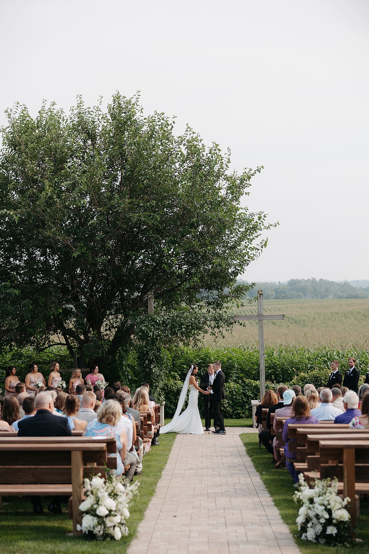 outdoor ceremony in front of large cross by Wisconsin wedding photographer