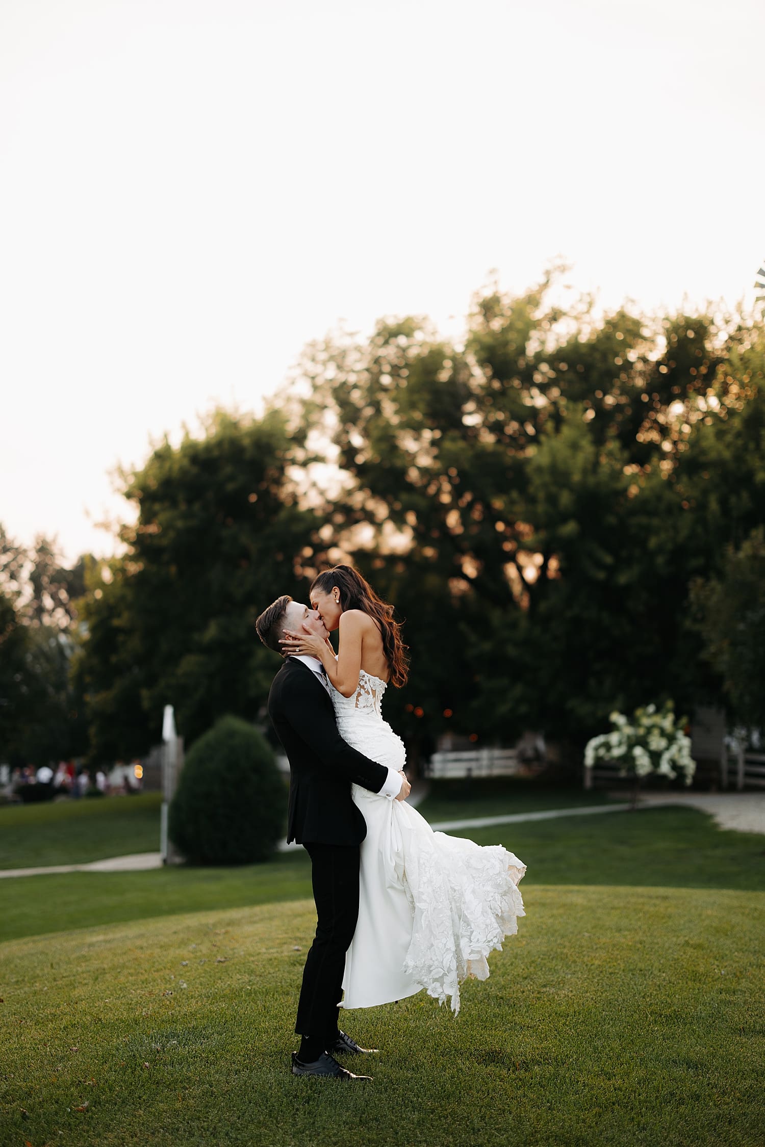 man lifts up his bride for kiss during golden hour by Rose and Oak Photography