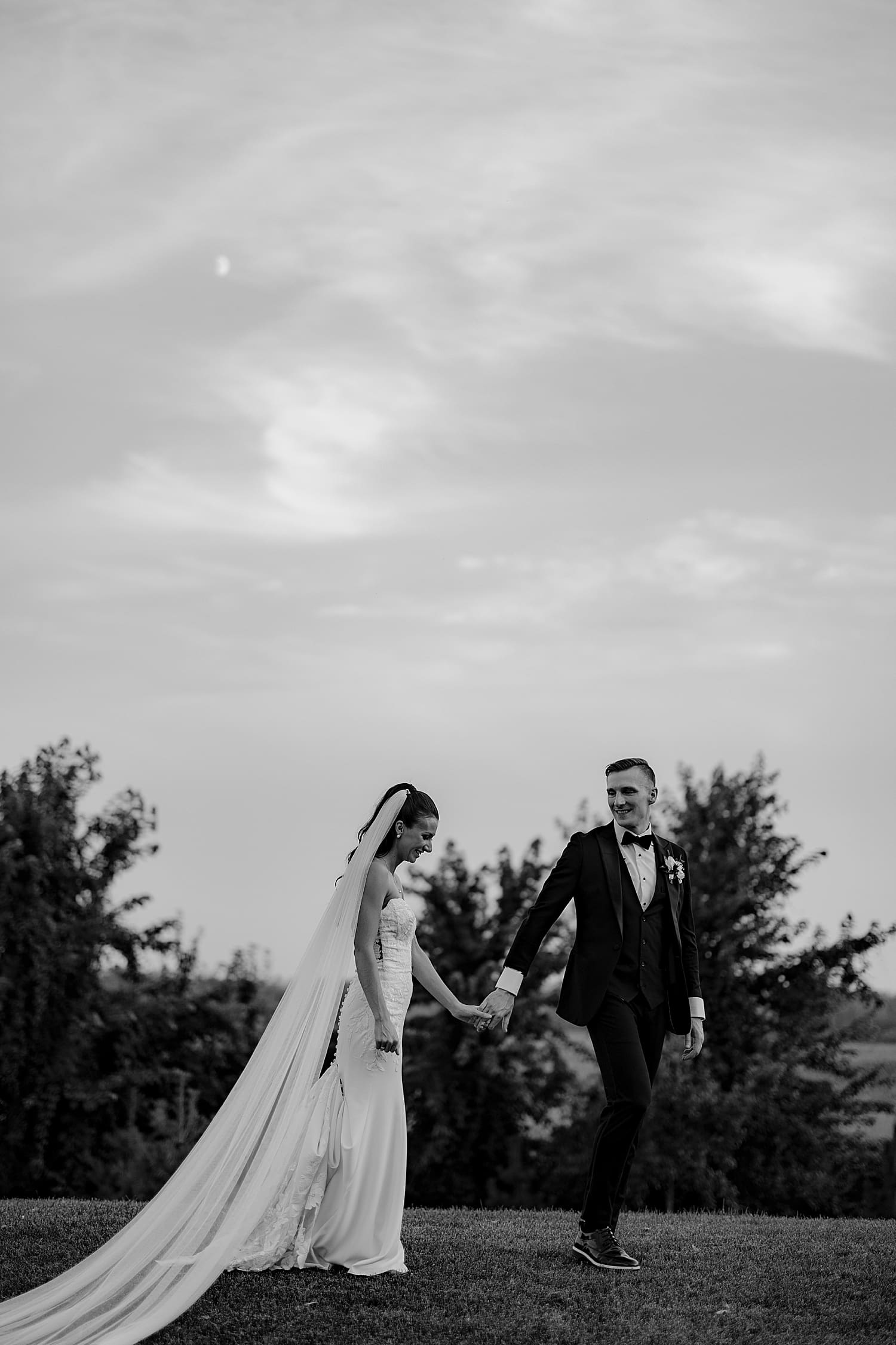 man leads woman across open field by Wisconsin wedding photographer