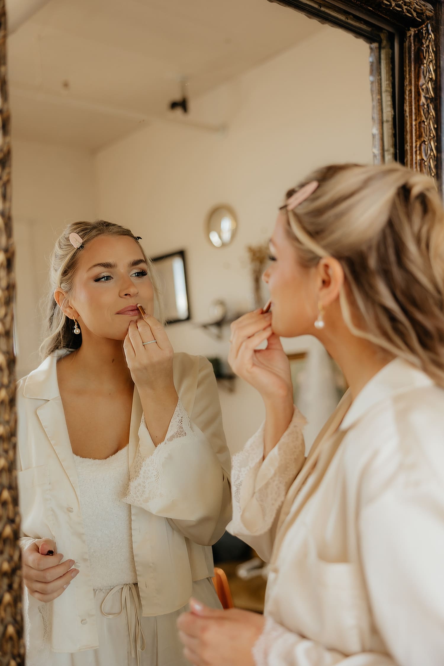woman puts on her lipstick in the mirror by Rose and Oak Photography