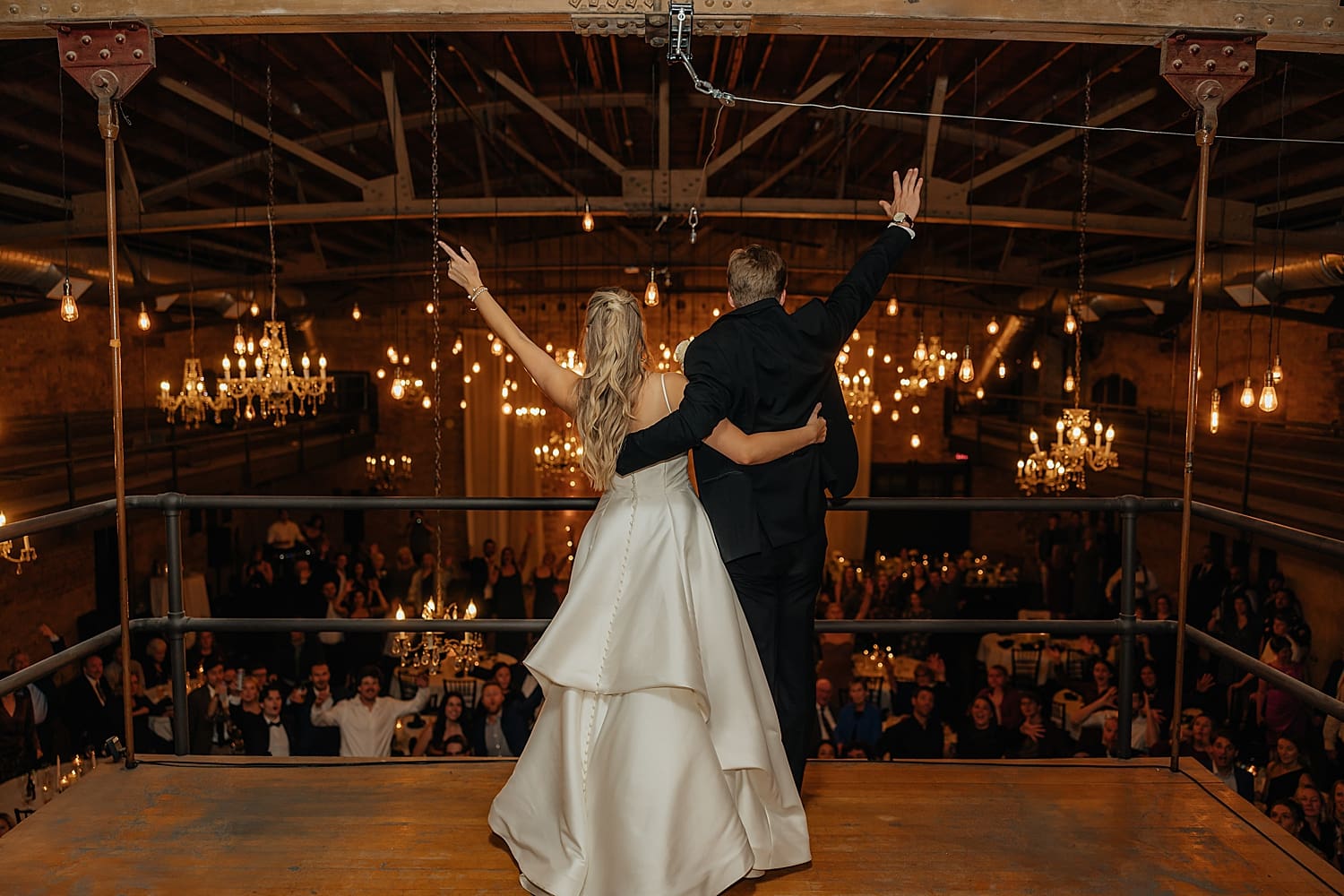 man and woman raise hands in celebration on balcony after learning 5 things to ask your wedding photographer