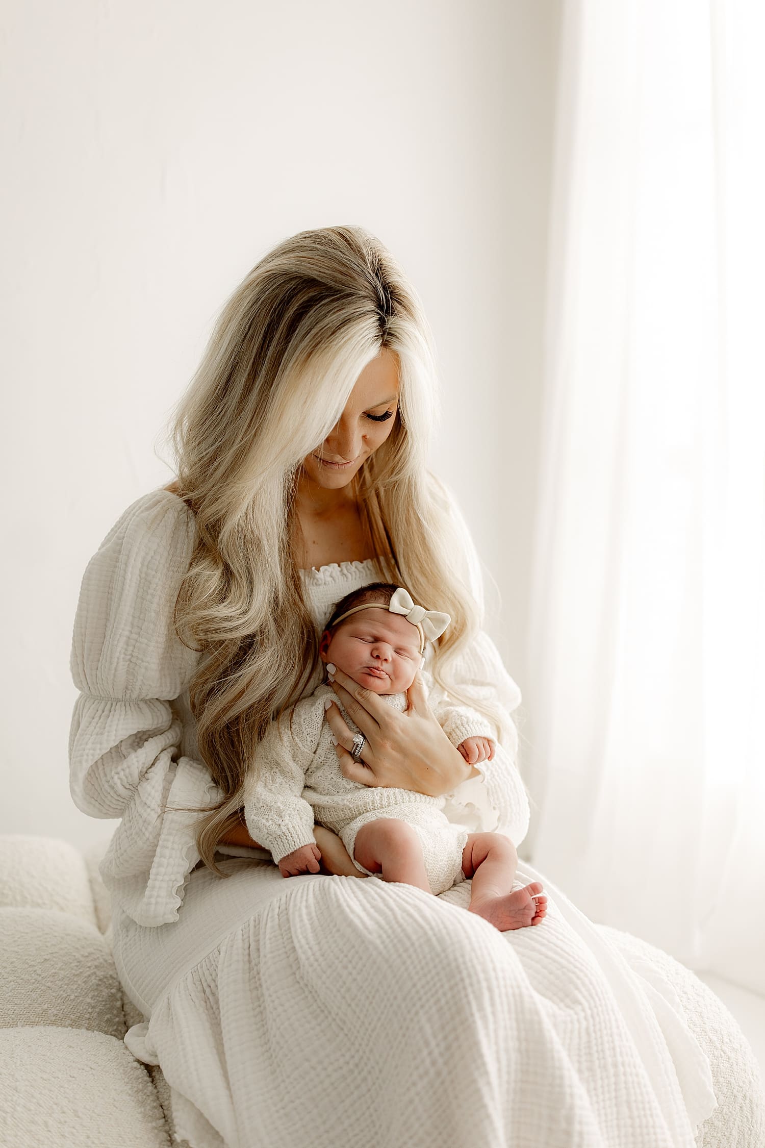 mama sits on Ottoman holding infant by Rose and Oak Photography