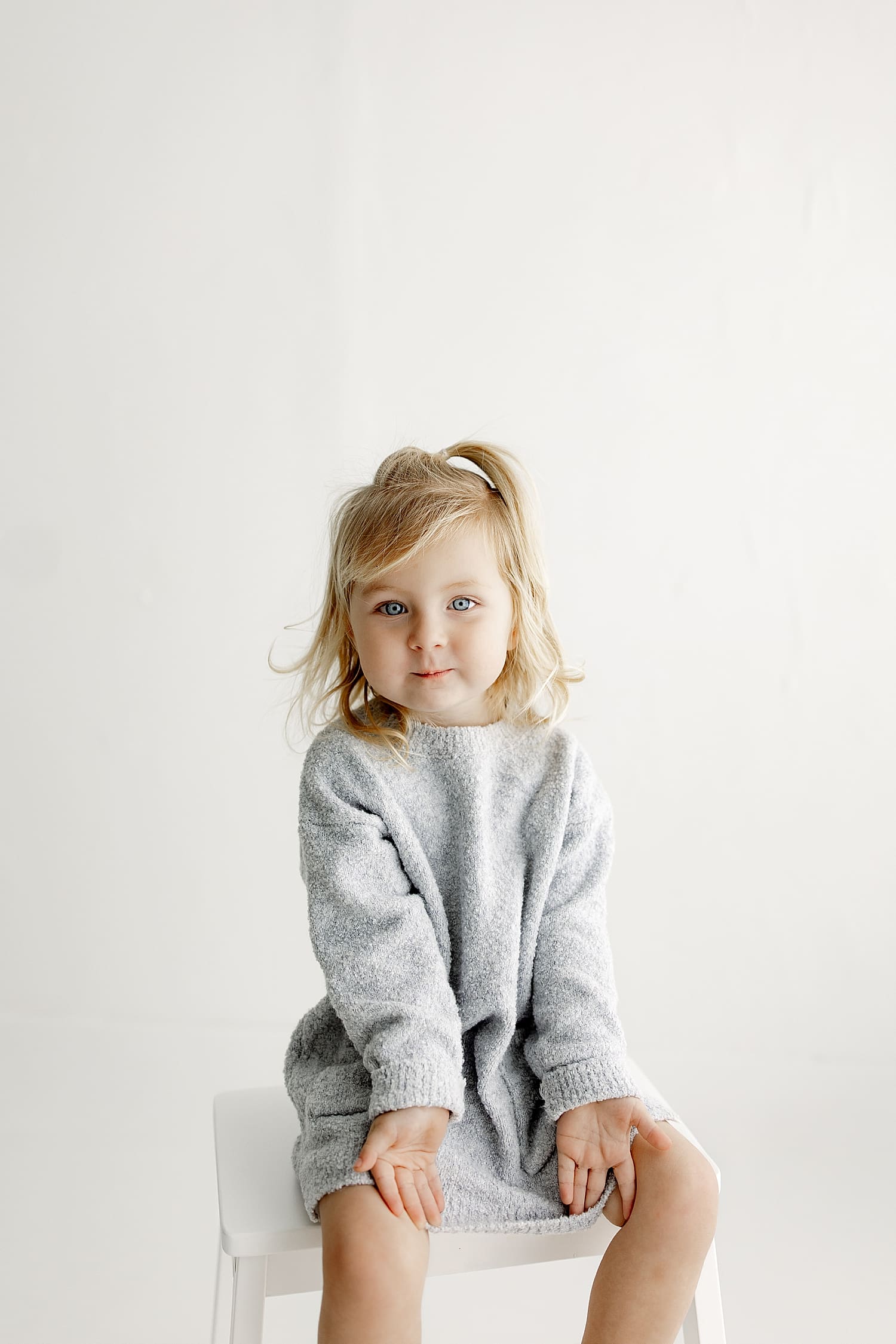 small girl in gray sweater dress on stool by Wisconsin family photographer