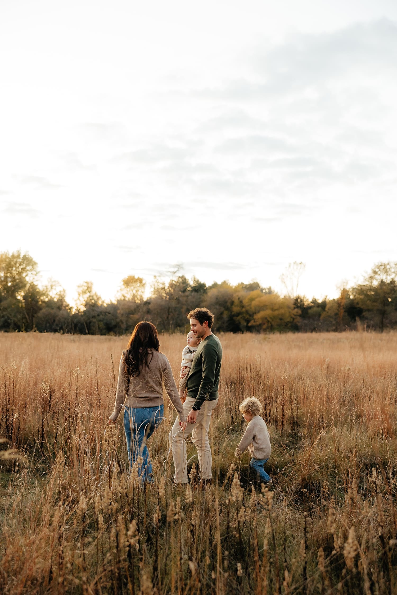 mother and father walk with their kids through field by Wisconsin photographer