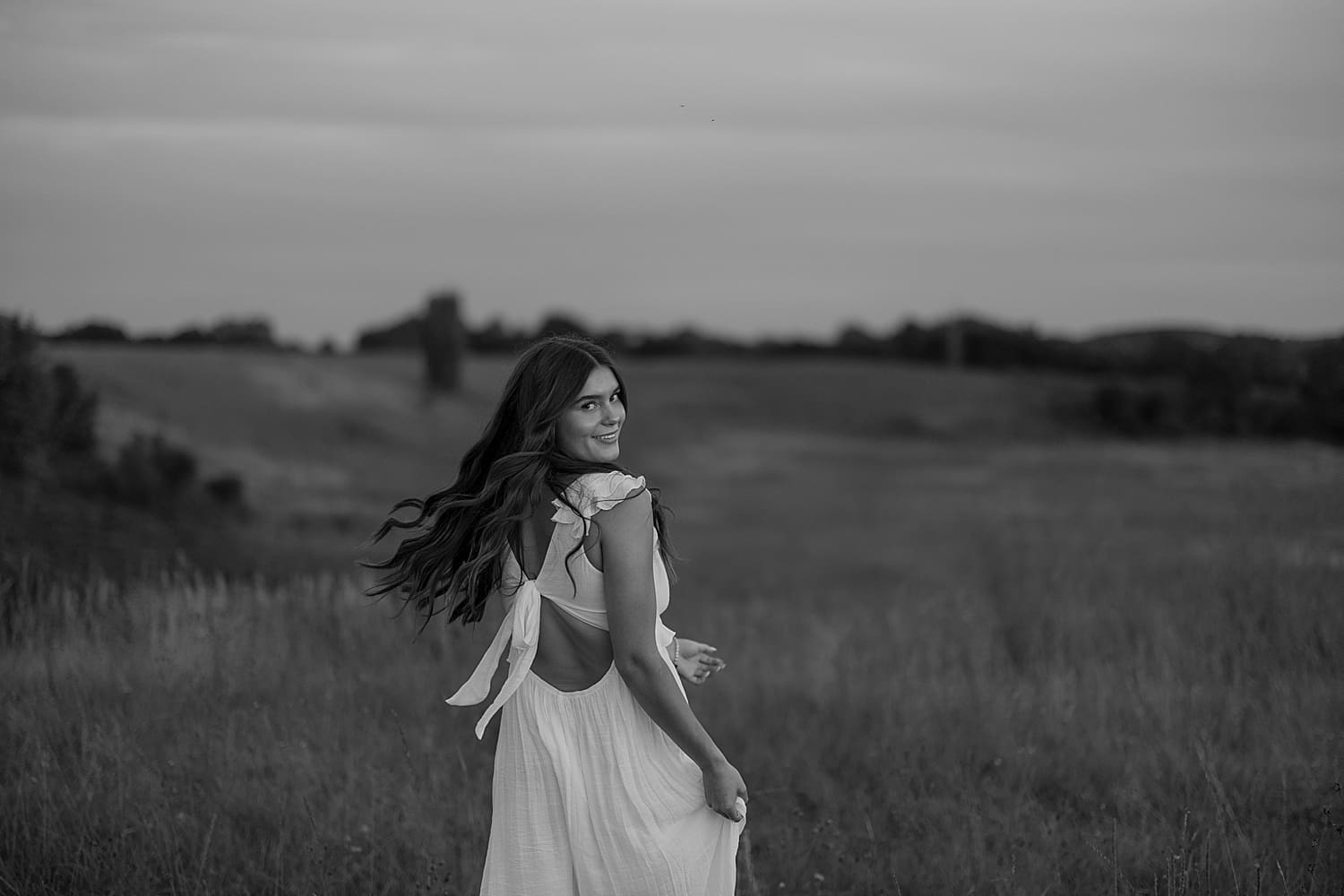 woman runs in field for golden hour senior session