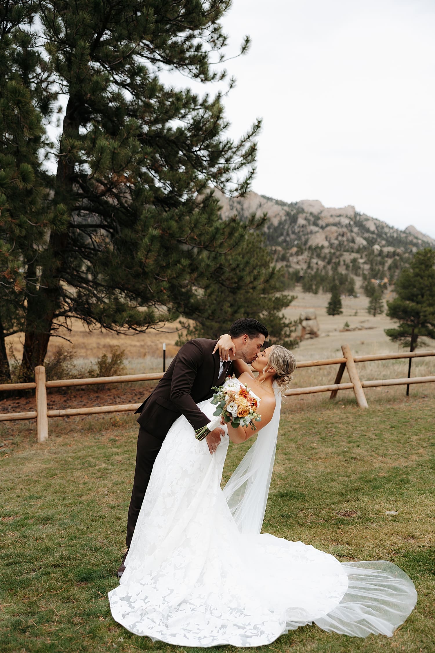 man dips woman for kiss in front of Colorado mountains by Rose and Oak Photography