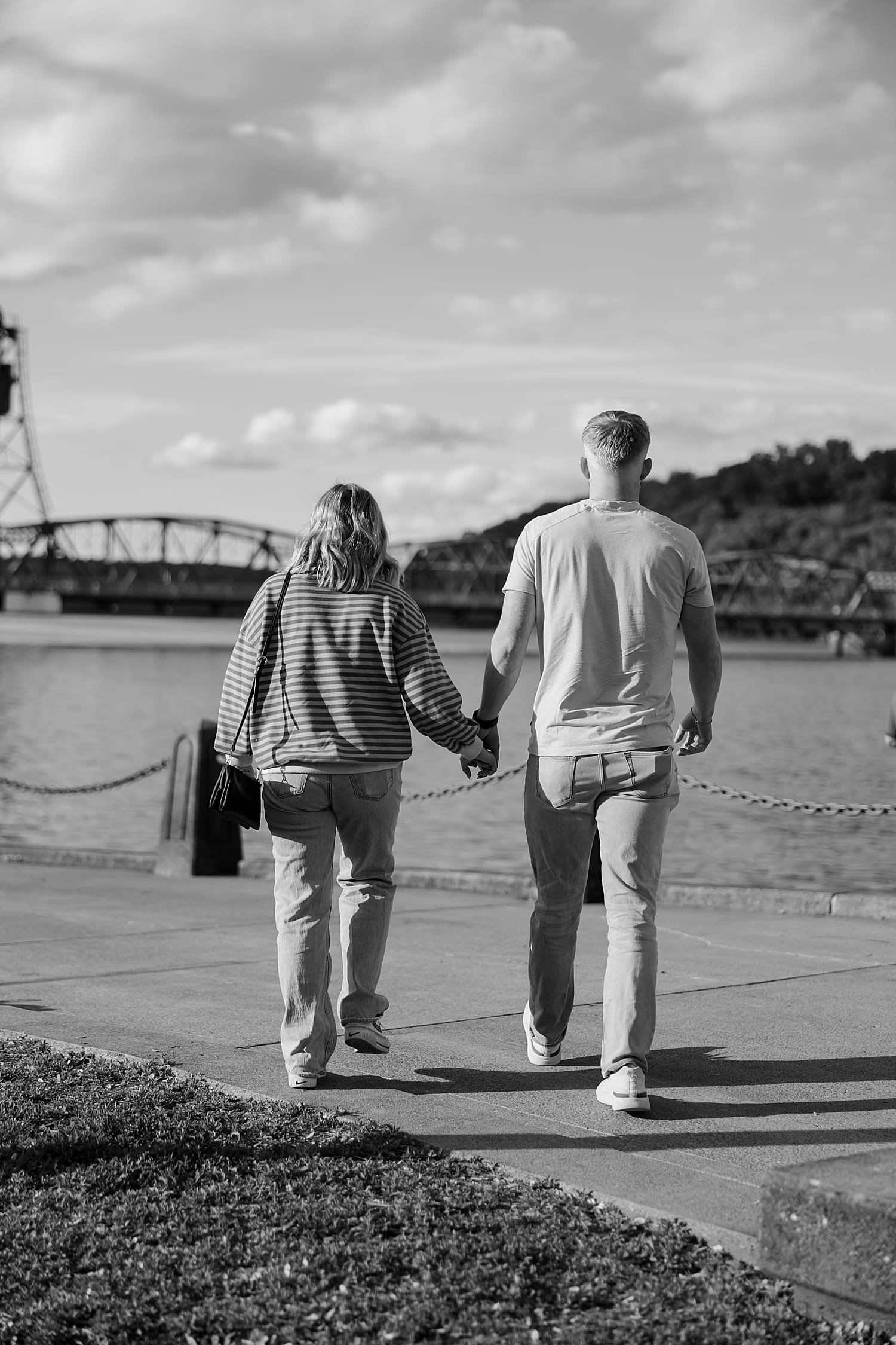 man and woman walk towards bridge for waterfront proposal