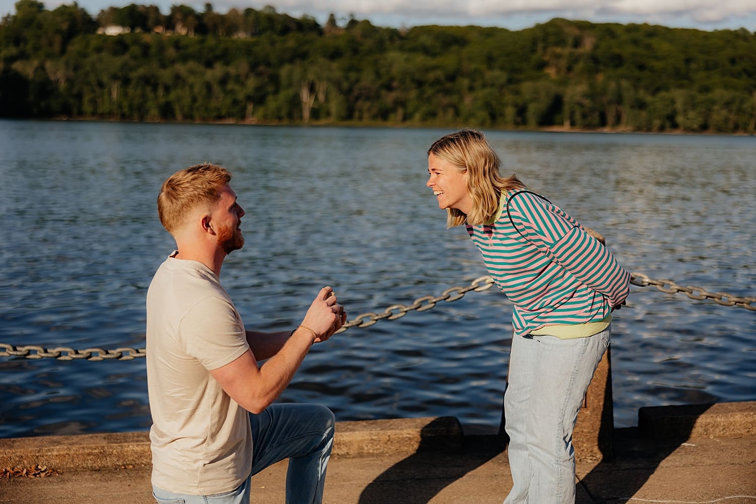 woman laughs in surprise as man holds up ring by Rose and Oak Photography