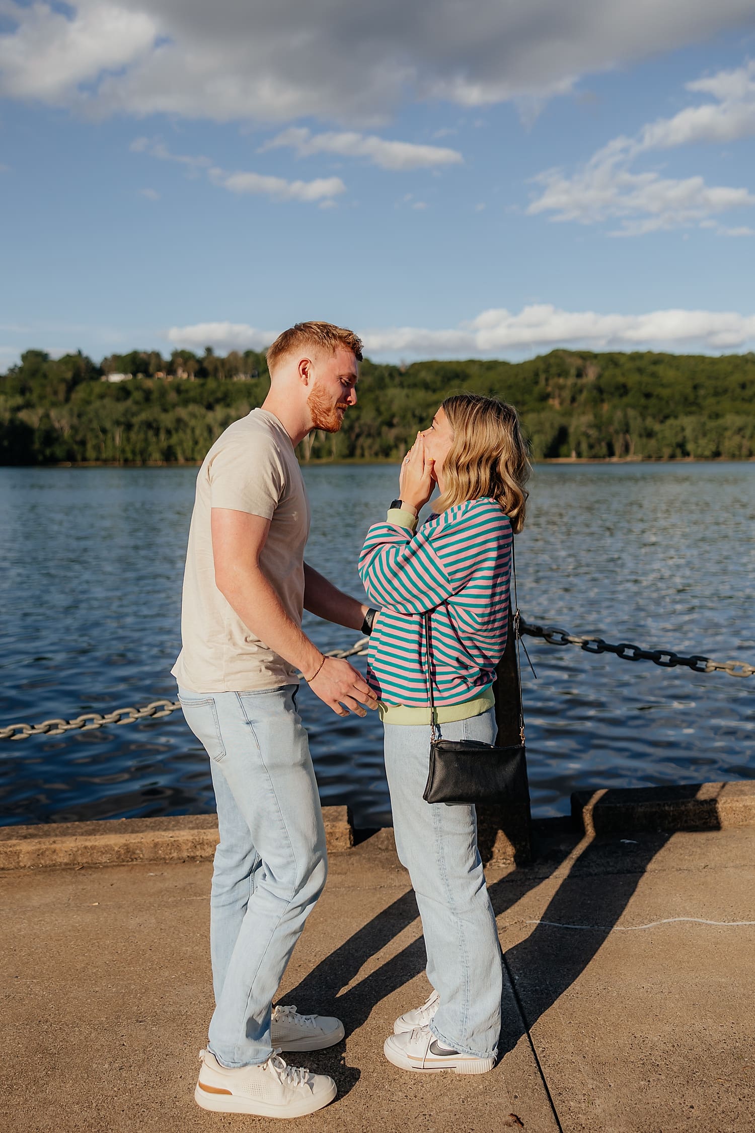 woman holds her mouth in surprise next to water by Wisconsin wedding photographer