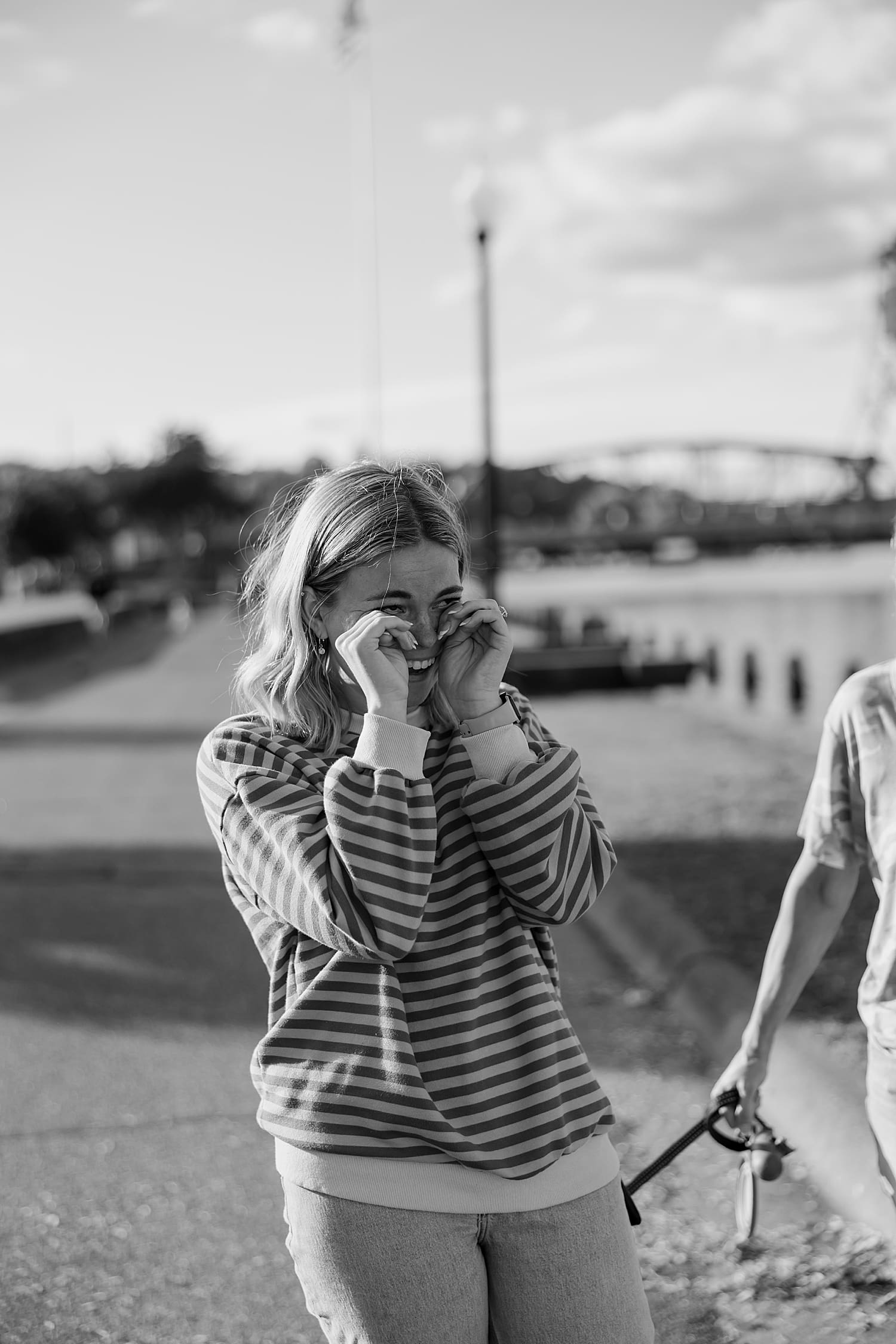 newly engaged woman wipes her eyes for waterfront proposal