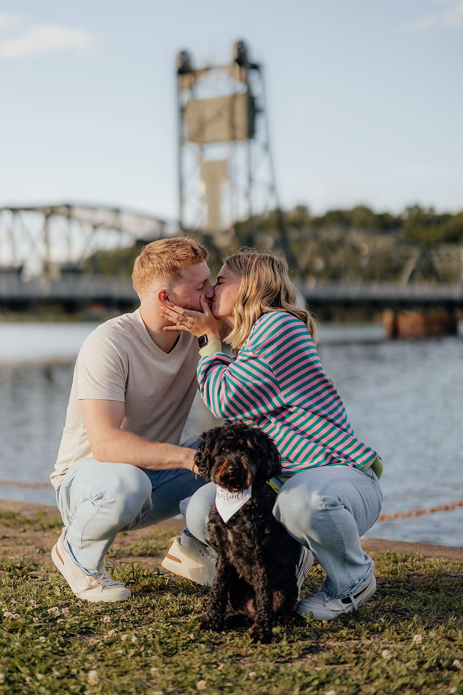 couple shares a kiss in front of bridge by Rose and Oak Photography