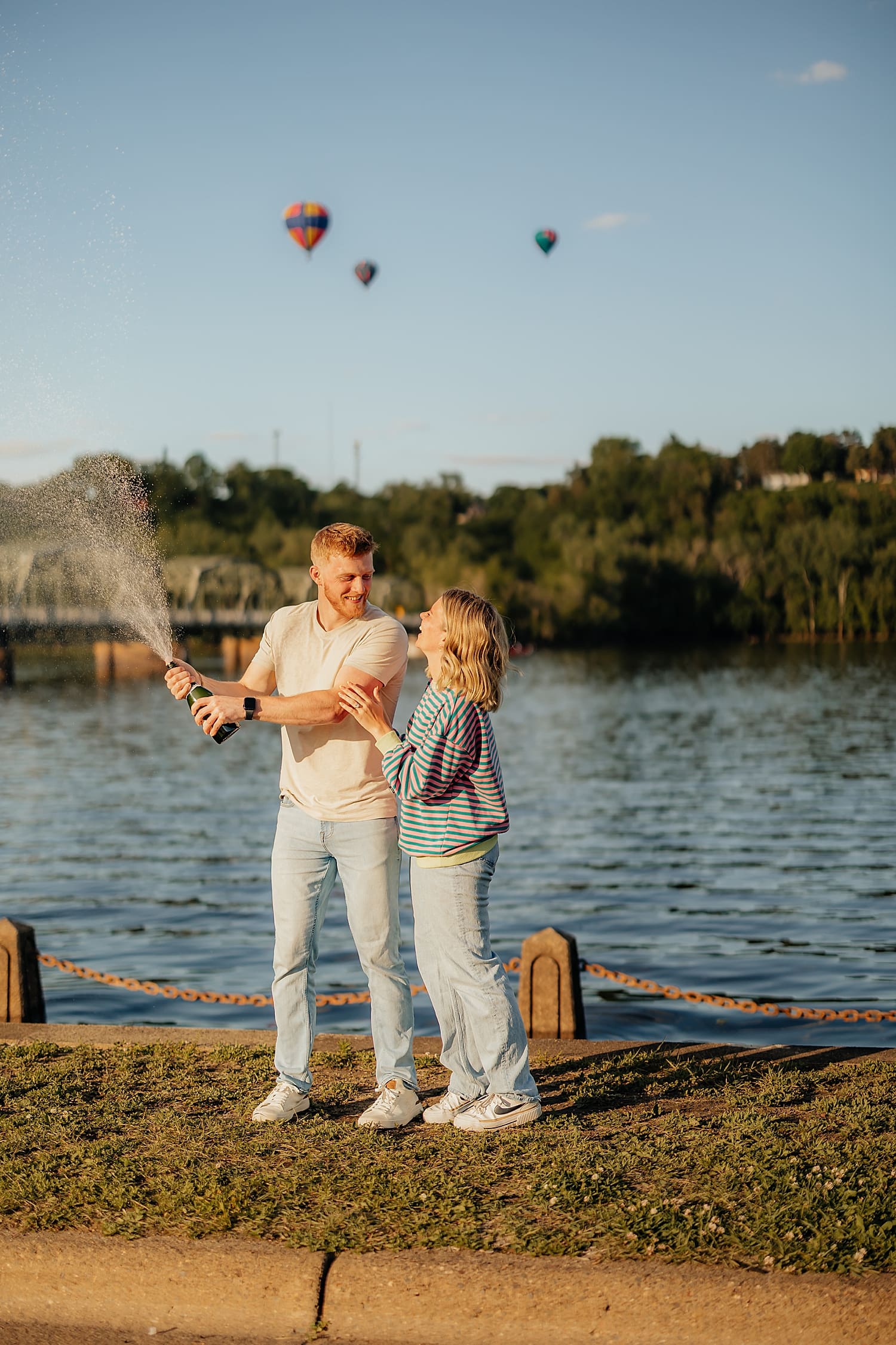 man sprays champagne while hot hair balloons float by by Rose and Oak Photography