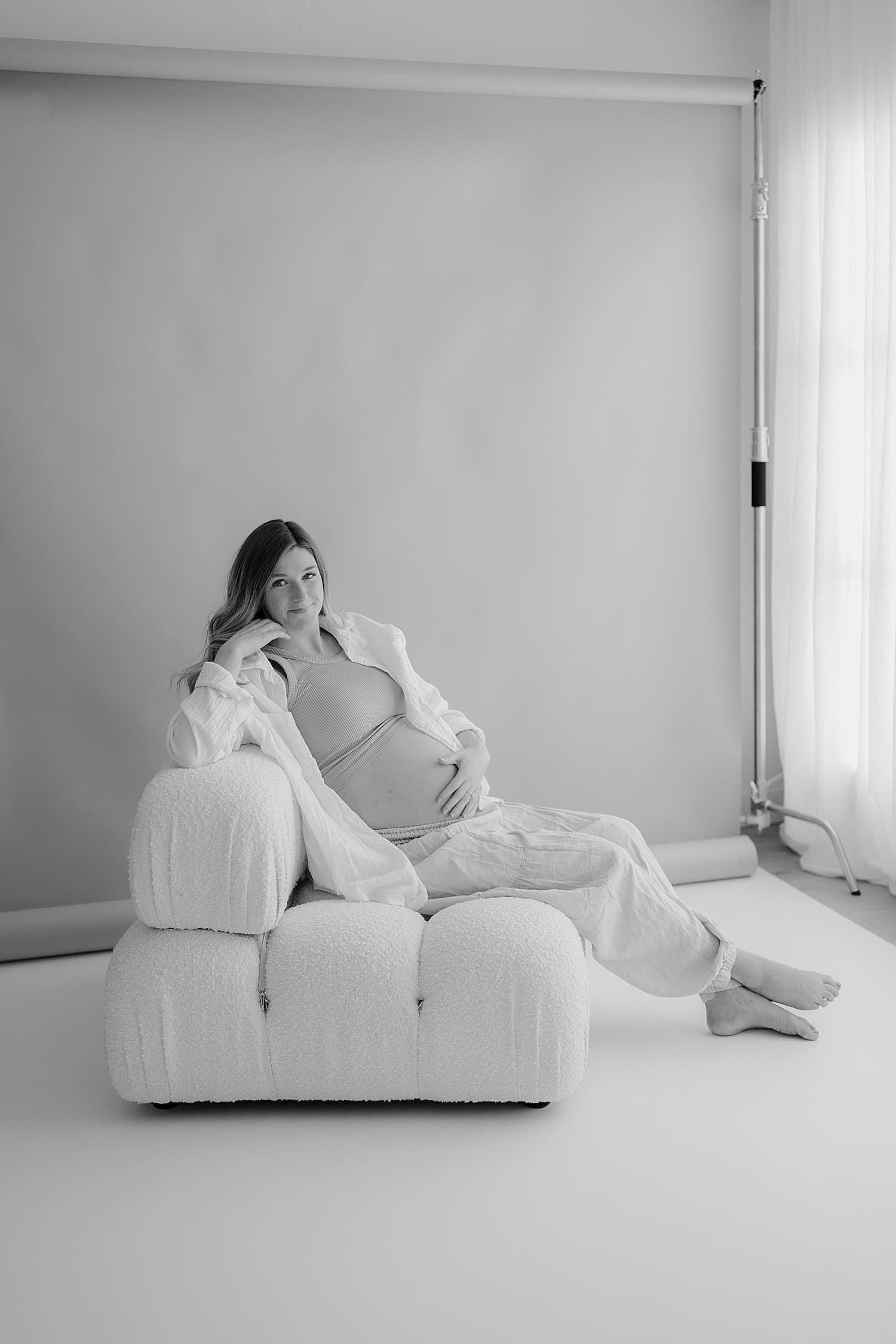 woman on white puffy chair in front of backdrop by Rose and Oak Photography