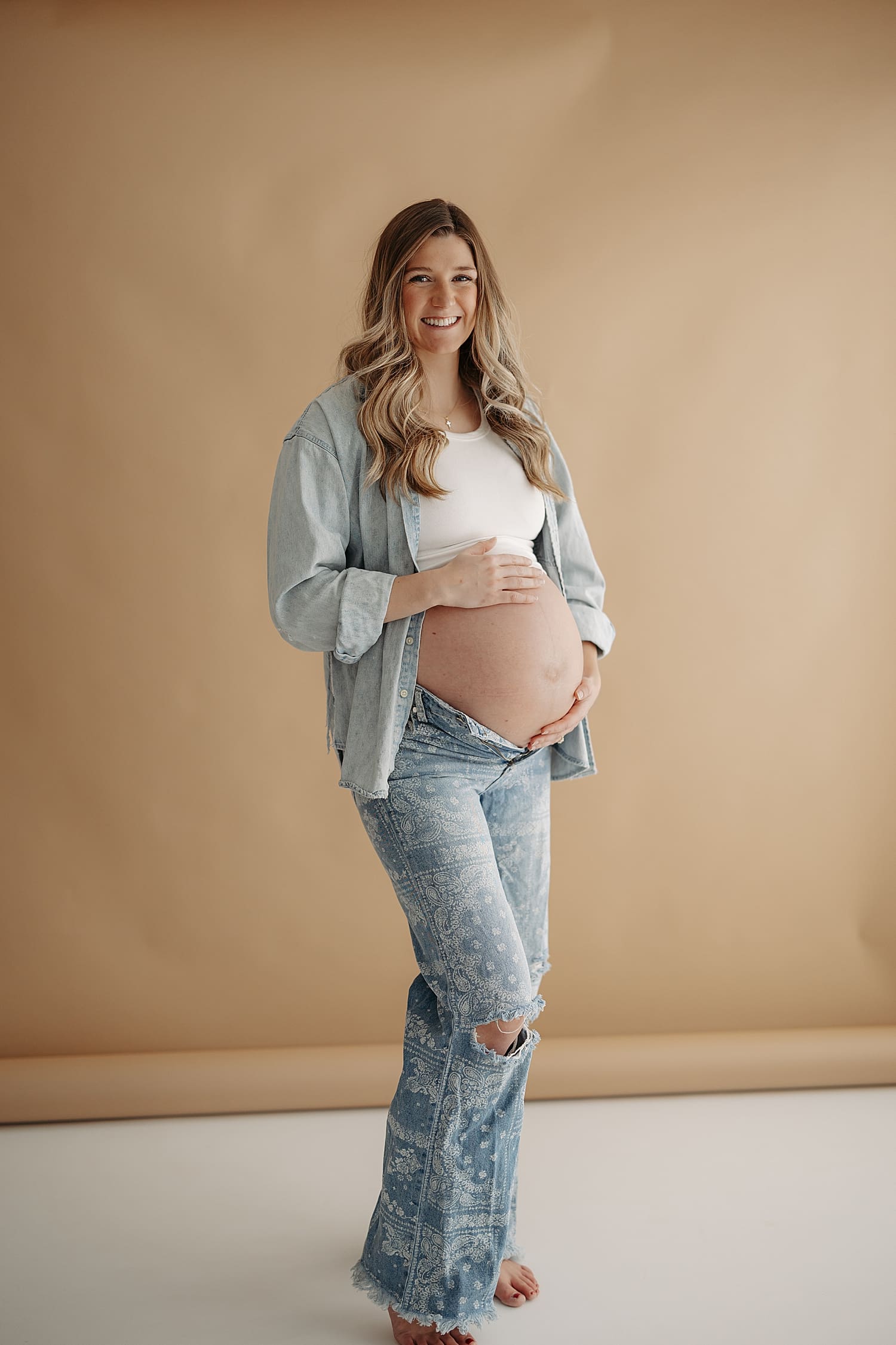 blonde mother stands in printed denim against backdrop by Rose and Oak Photography