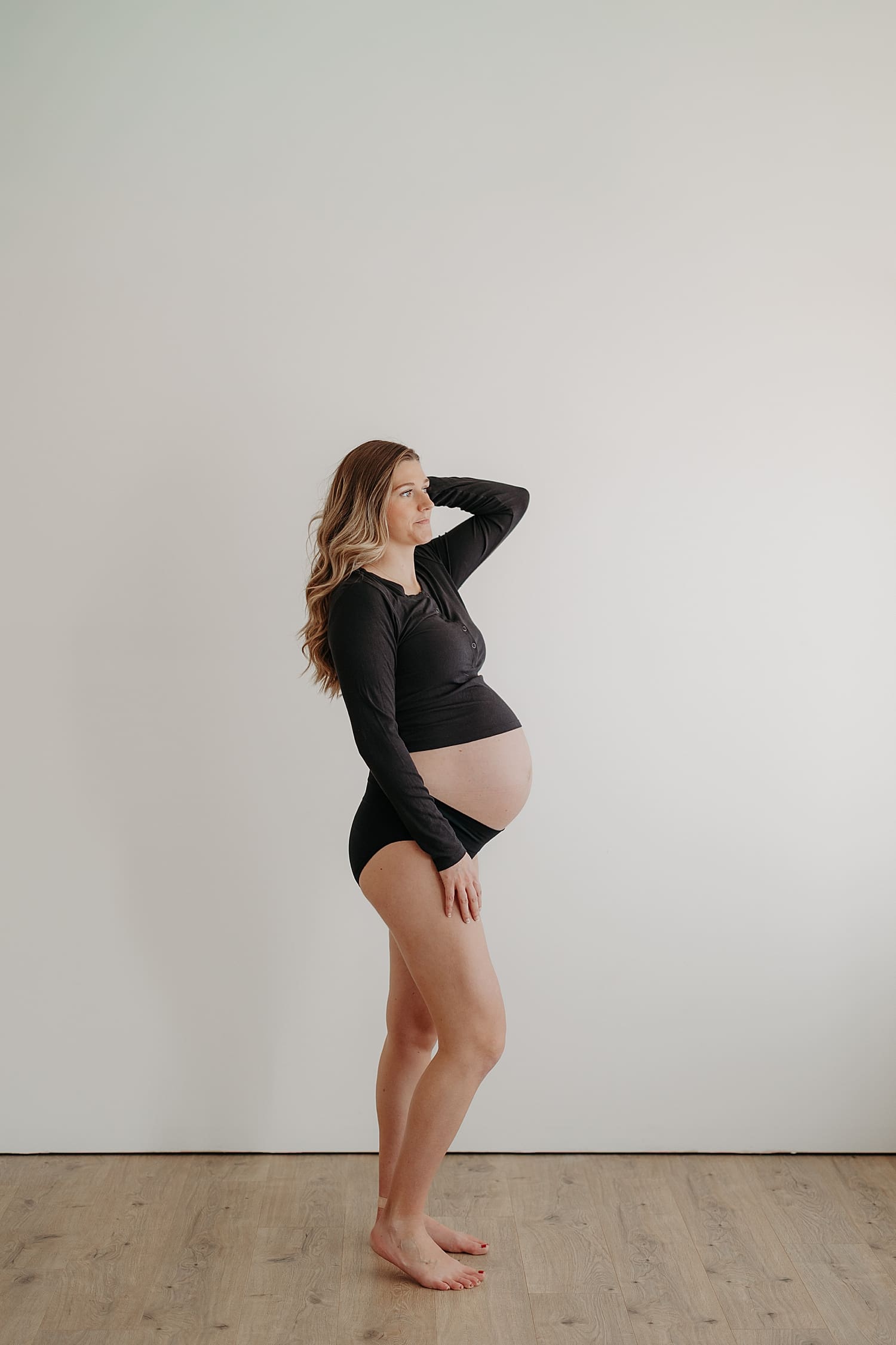 blonde stands in underwear next to white wall by Wisconsin family photographer