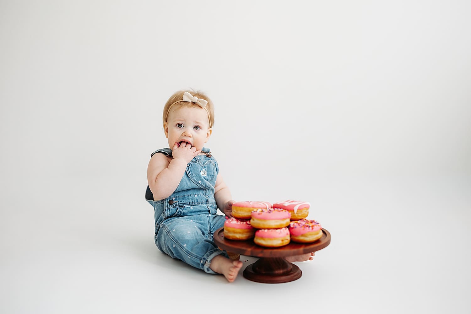 baby sits on studio floor eating donuts by Wisconsin family photographer