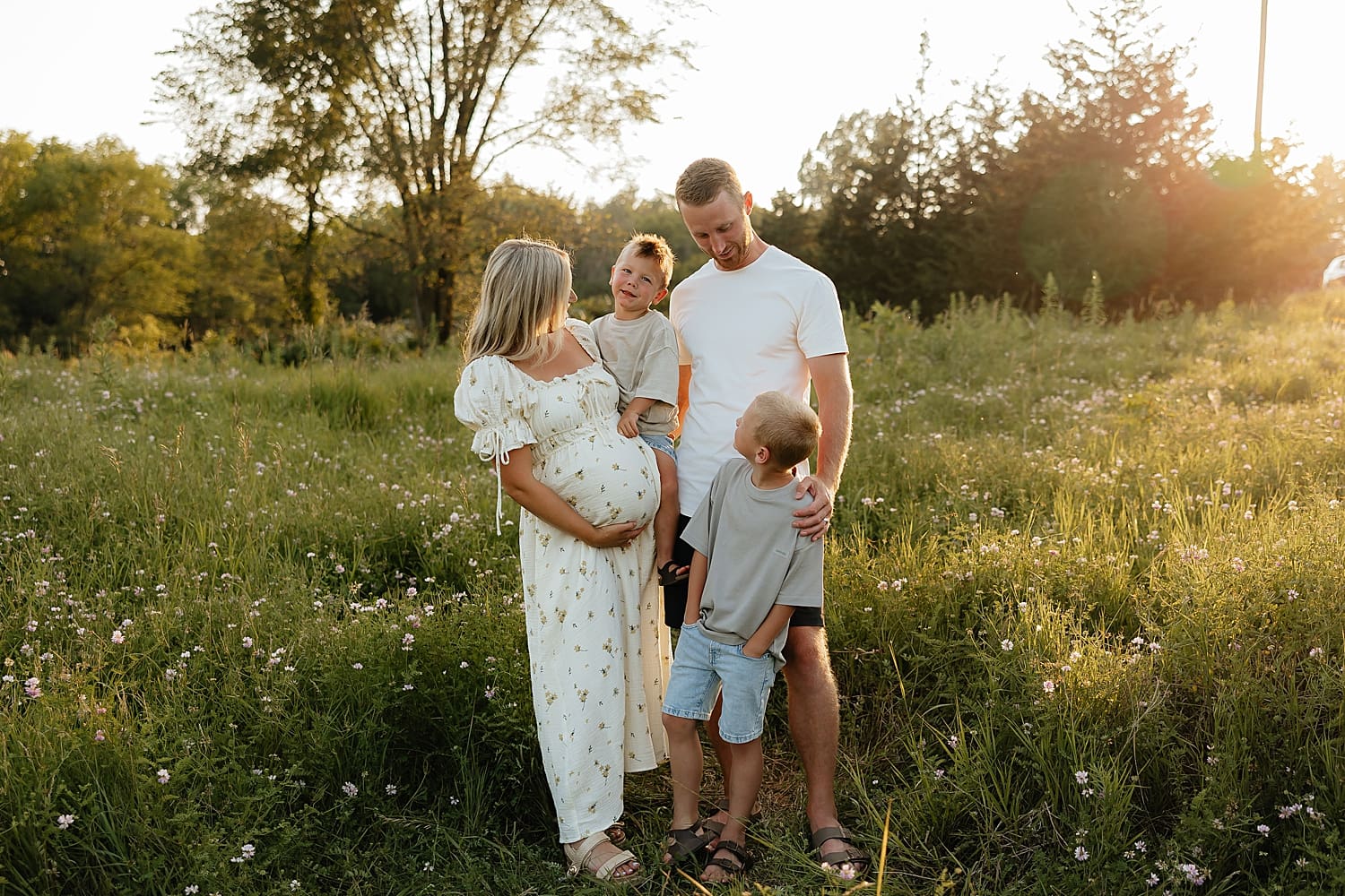 family of four snuggles up together in Summer outdoors by Rose and Oak Photography
