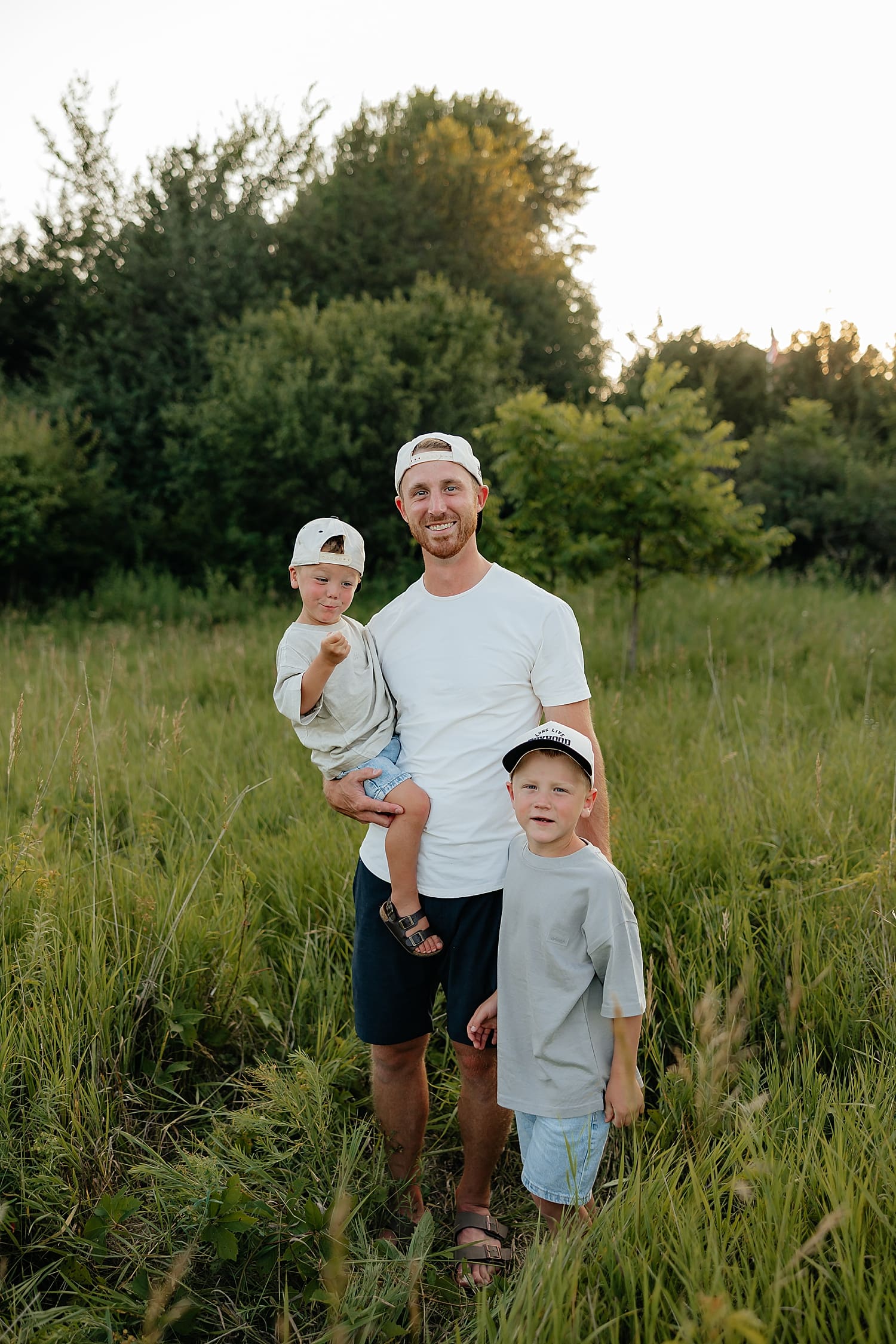 dad and his two young sons stand in tall grass by Wisconsin family photographer