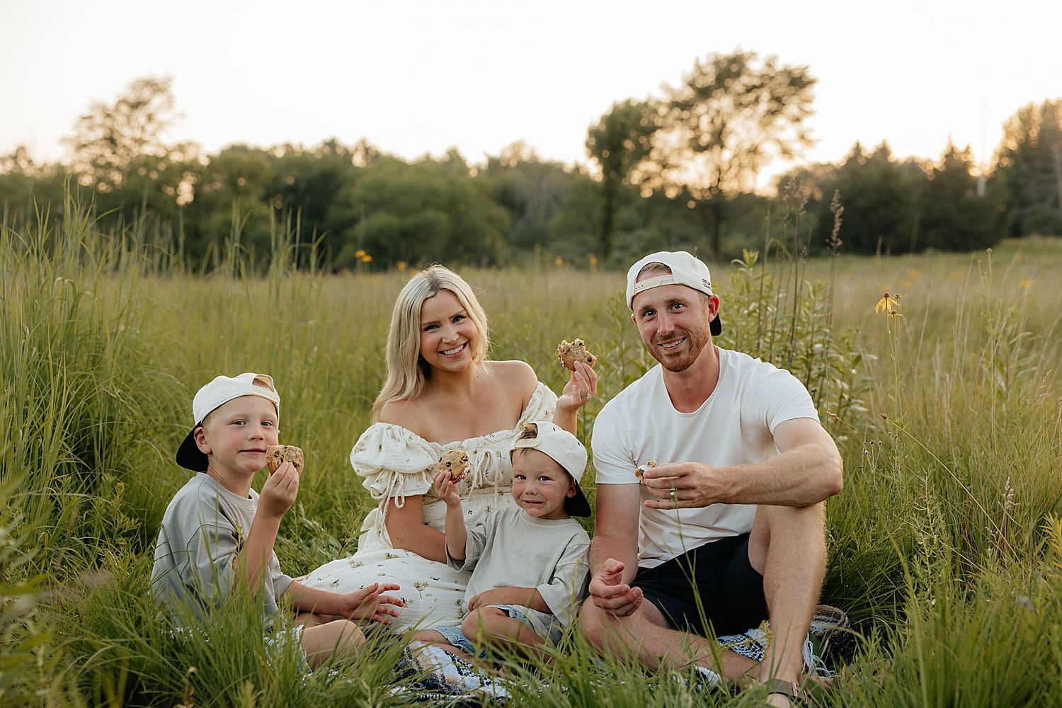 family of four shares ice cream sandwiches in field by Rose and Oak Photography