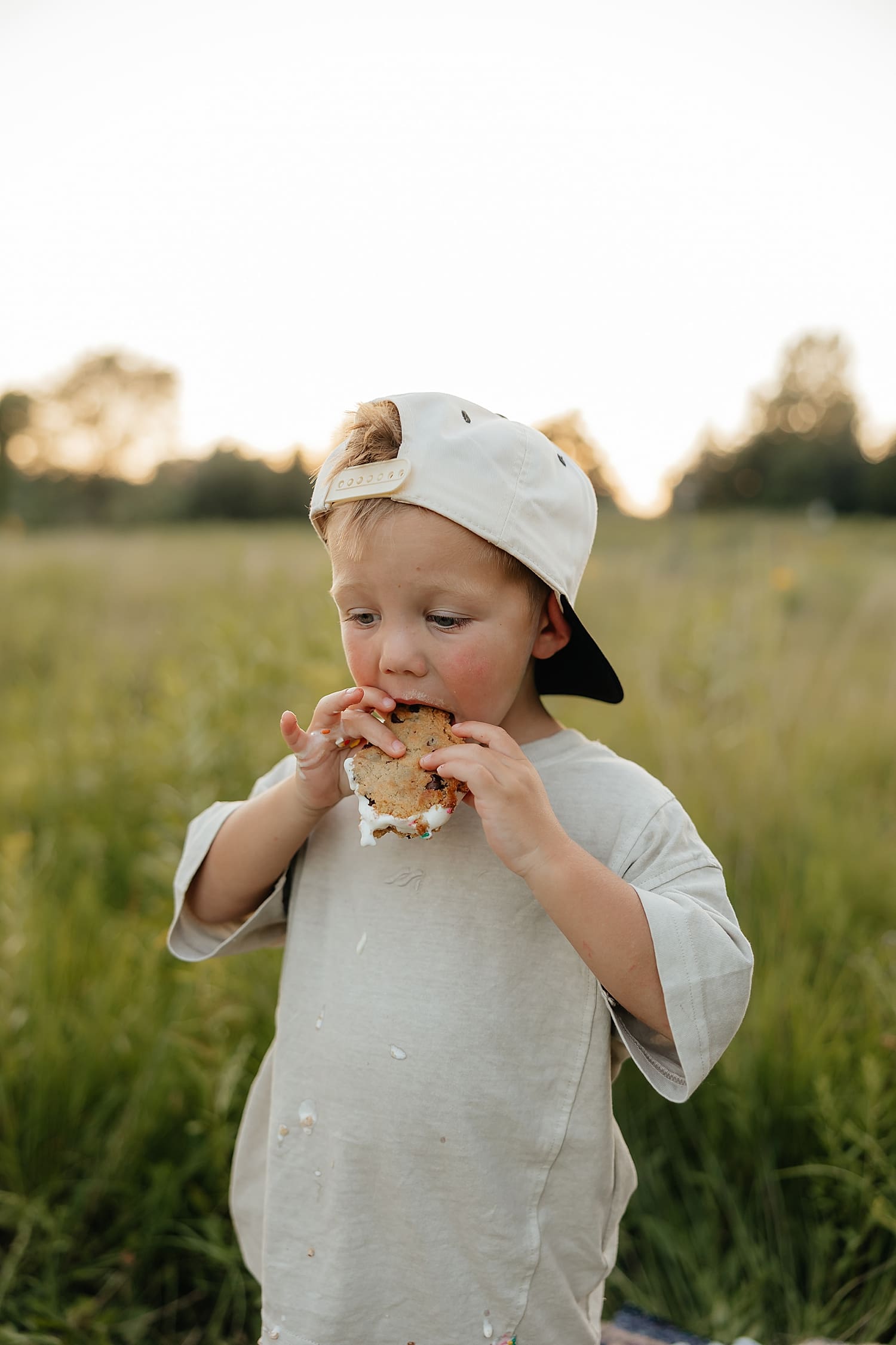 toddler boy with backwards cap eats ice cream sandwich by Wisconsin family photographer