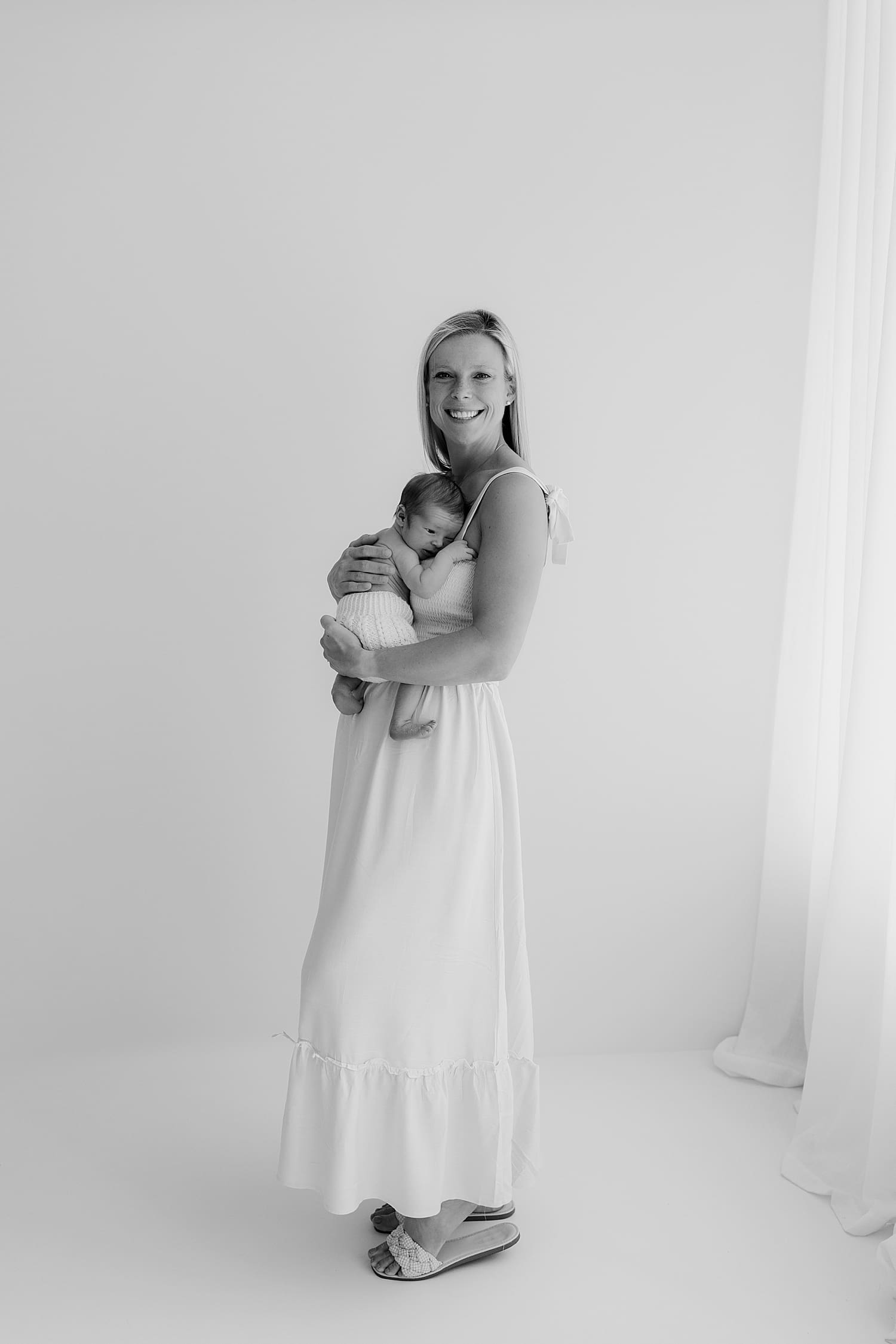 mama holds baby next to window for neutral newborn session