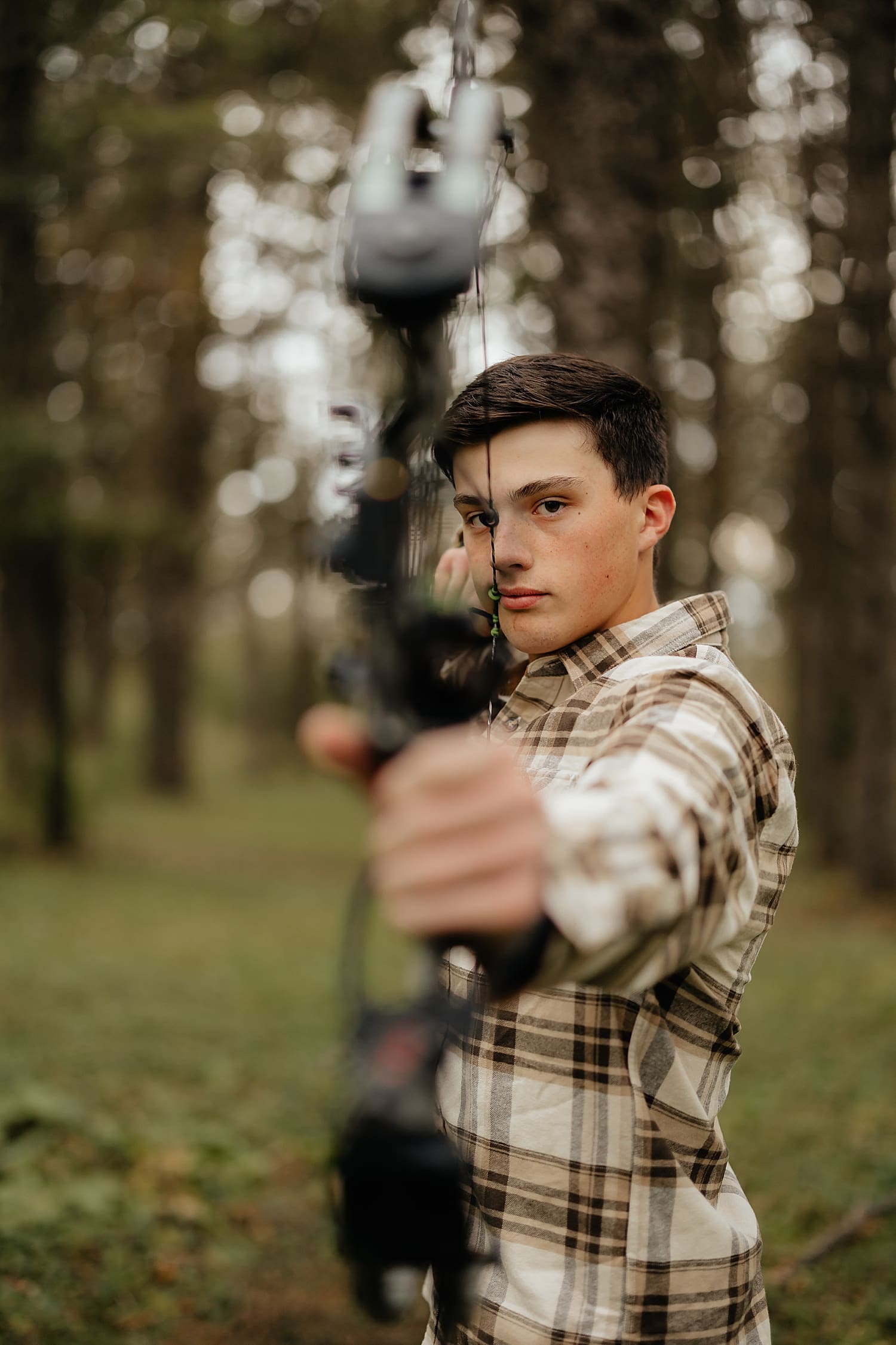 graduating teen shows off hunting bow by Rose and Oak Photography