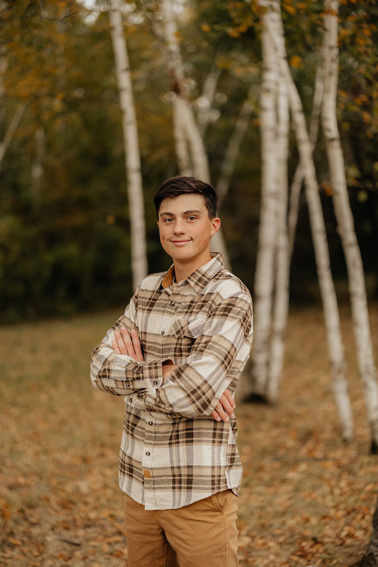 graduating student stands in front of tall white trees by Wisconsin family photographer